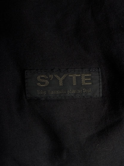 Close-up of a black woven fabric label with the brand name 'S'YTE' and the text 'Yokohama plastic bag' stitched in a contrasting light tone.