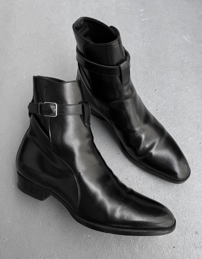 Pair of black leather boots with buckle details on a gray background