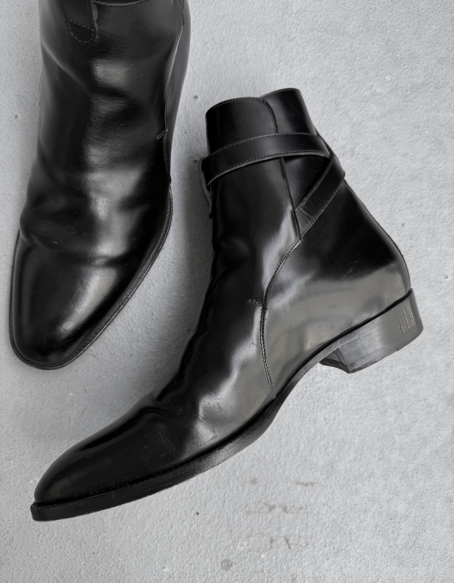 Pair of black leather boots on a light gray background