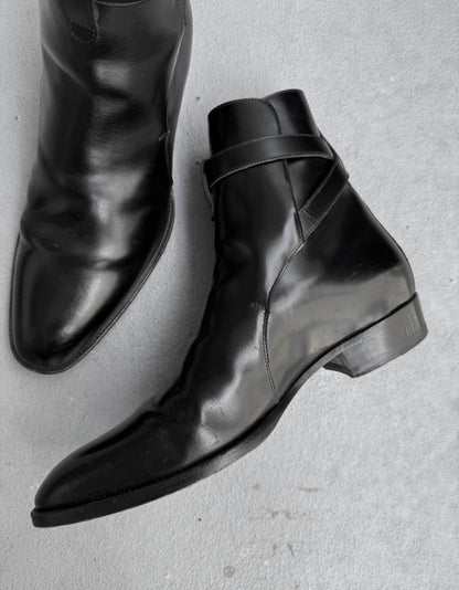 Pair of black leather boots on a light gray background
