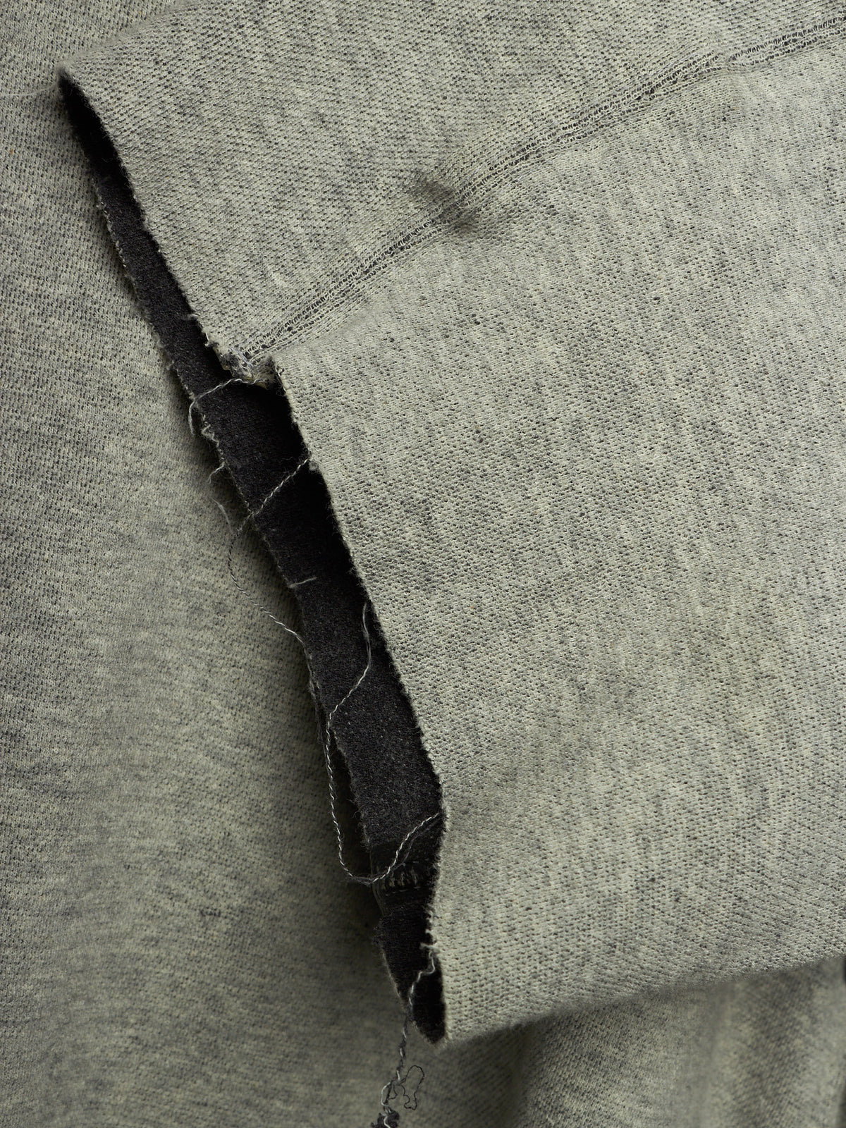 Close-up of a heather gray knit fabric with a folded edge showing a dark inner lining or backing.
