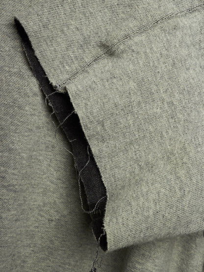 Close-up of a heather gray knit fabric with a folded edge showing a dark inner lining or backing.