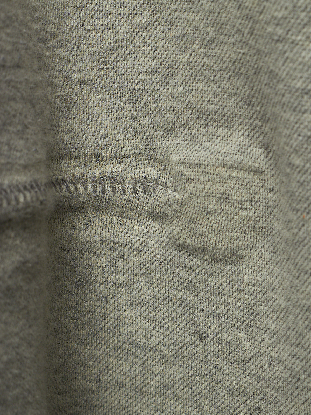 Close-up of a heather gray knit fabric with a visible horizontal seam and slight texture detail.