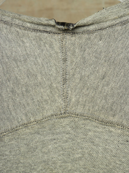 Close-up of a heather gray knit garment, showing the back neckline with a small dark tag or label attached at the collar.
