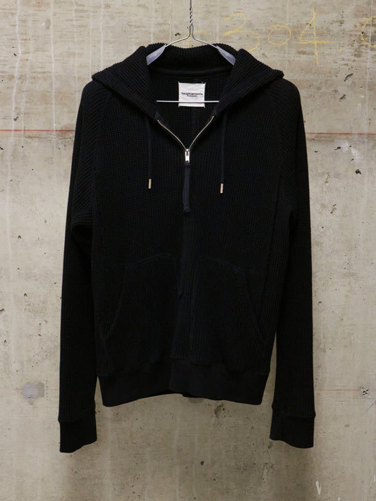 Black hoodie on a hanger against a textured beige wall