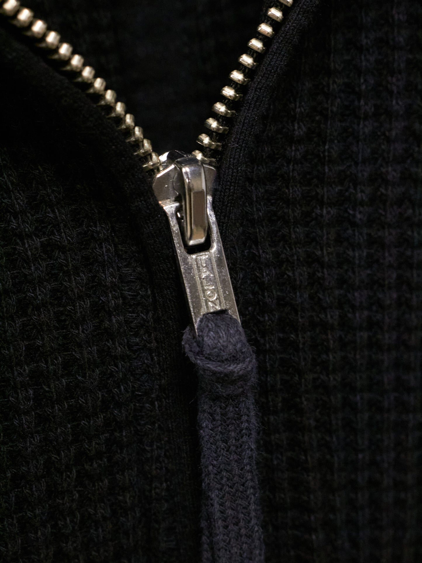 Close-up of a zipper on a black textured fabric background