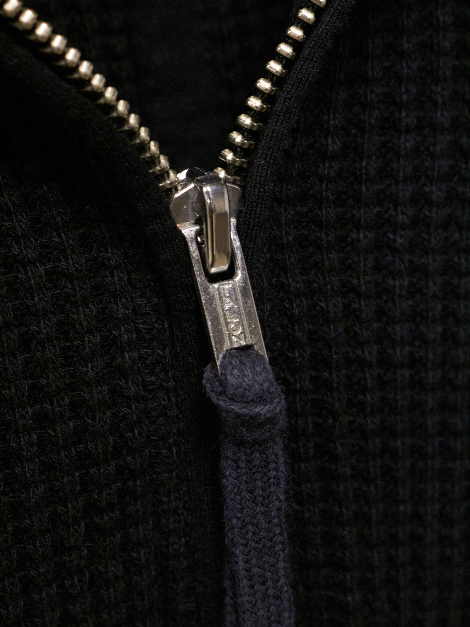 Close-up of a zipper on a black textured fabric background