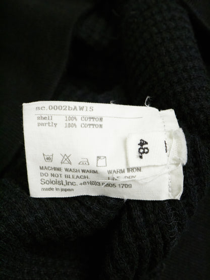 Clothing label on a black garment with text and symbols.
