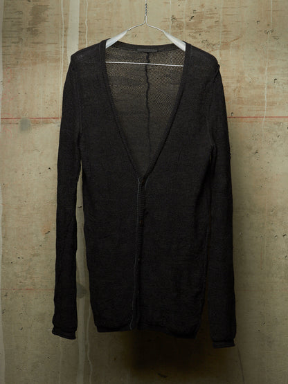 A black open-front cardigan sweater with a deep V-neck and long sleeves, hanging on a white plastic hanger against a textured concrete wall.