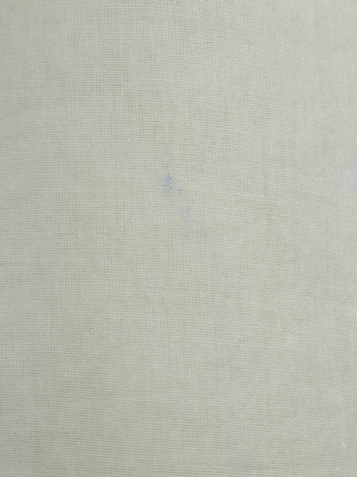 A close-up of a light beige textured fabric with a fine woven linen-like pattern.