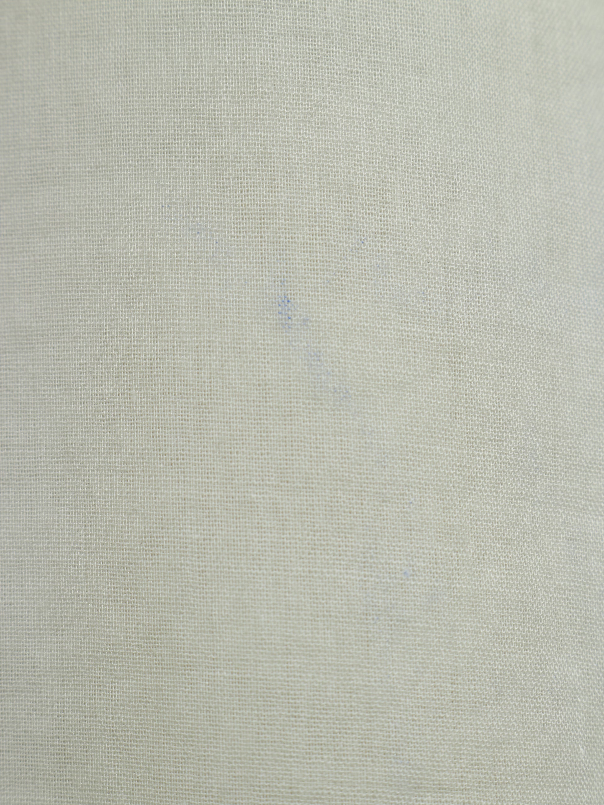 A close-up of a light beige textured fabric with a fine woven linen-like pattern.