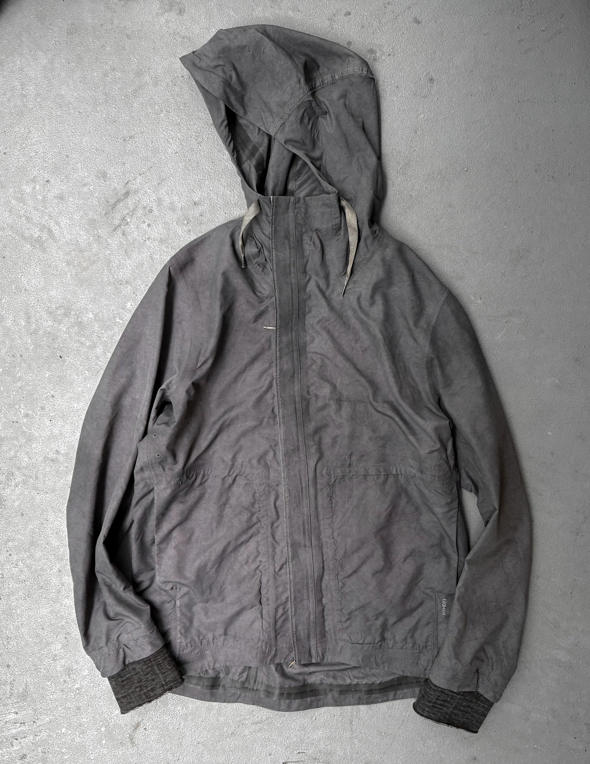 Dark gray hooded jacket on a textured gray surface