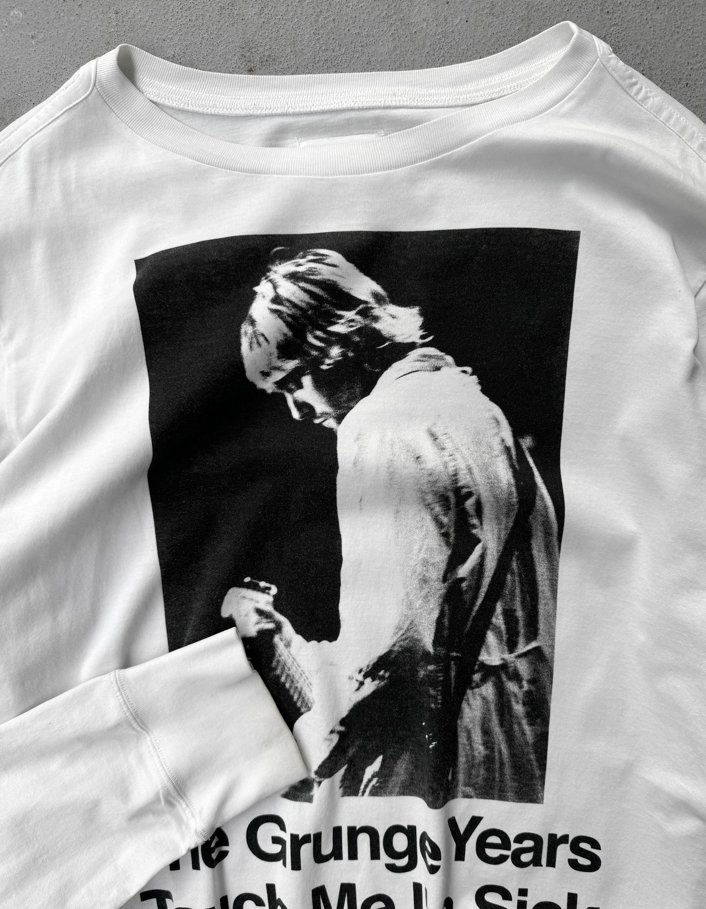 White sweatshirt with a graphic of a person and text 'The Grungy Years Taught Me to Smile' on a gray background