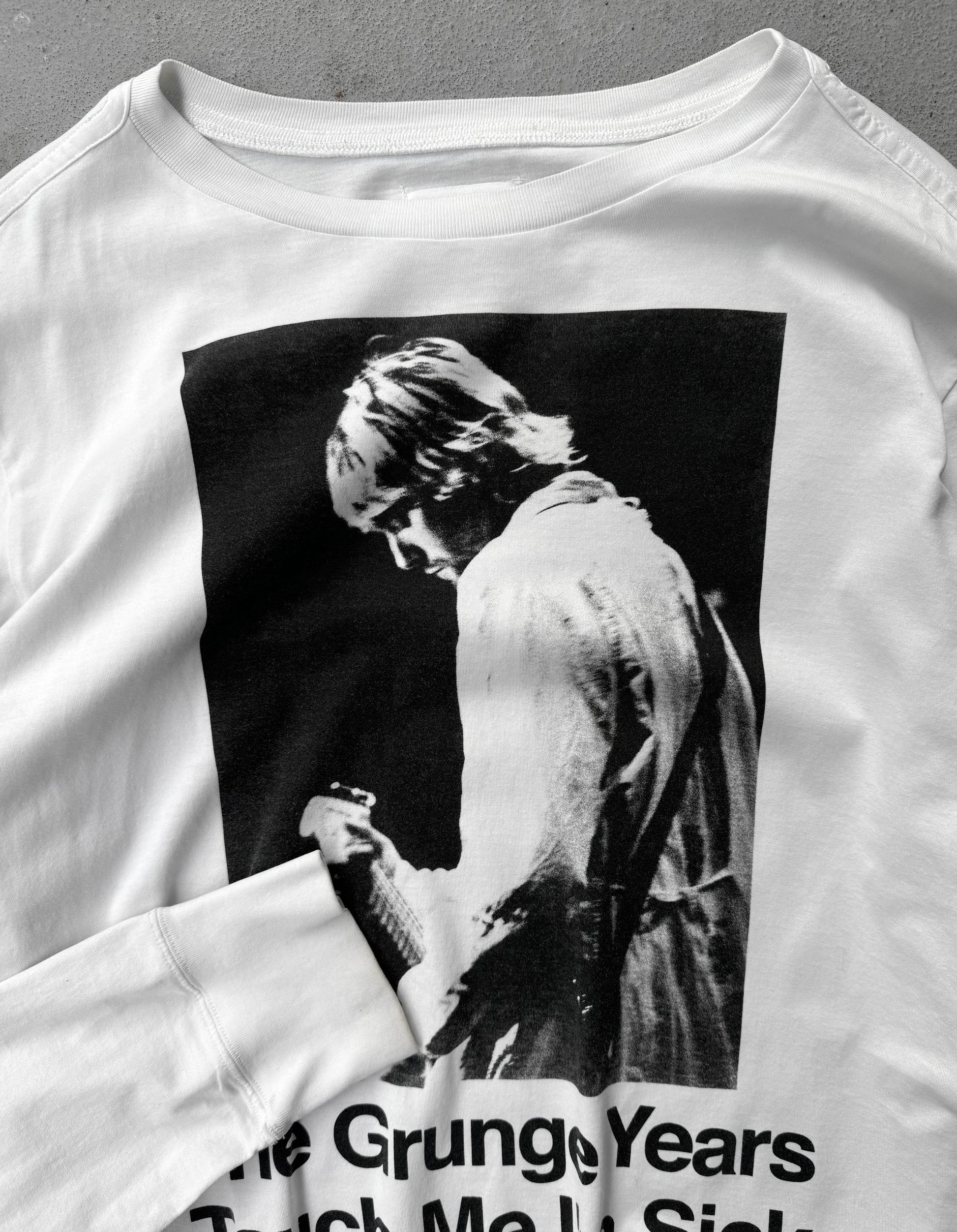 White sweatshirt with a graphic of a person and text 'The Grungy Years Taught Me to Smile' on a gray background