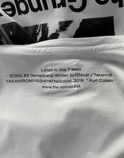 Close-up of a white t-shirt with text on it, featuring a black and white photo in the background.