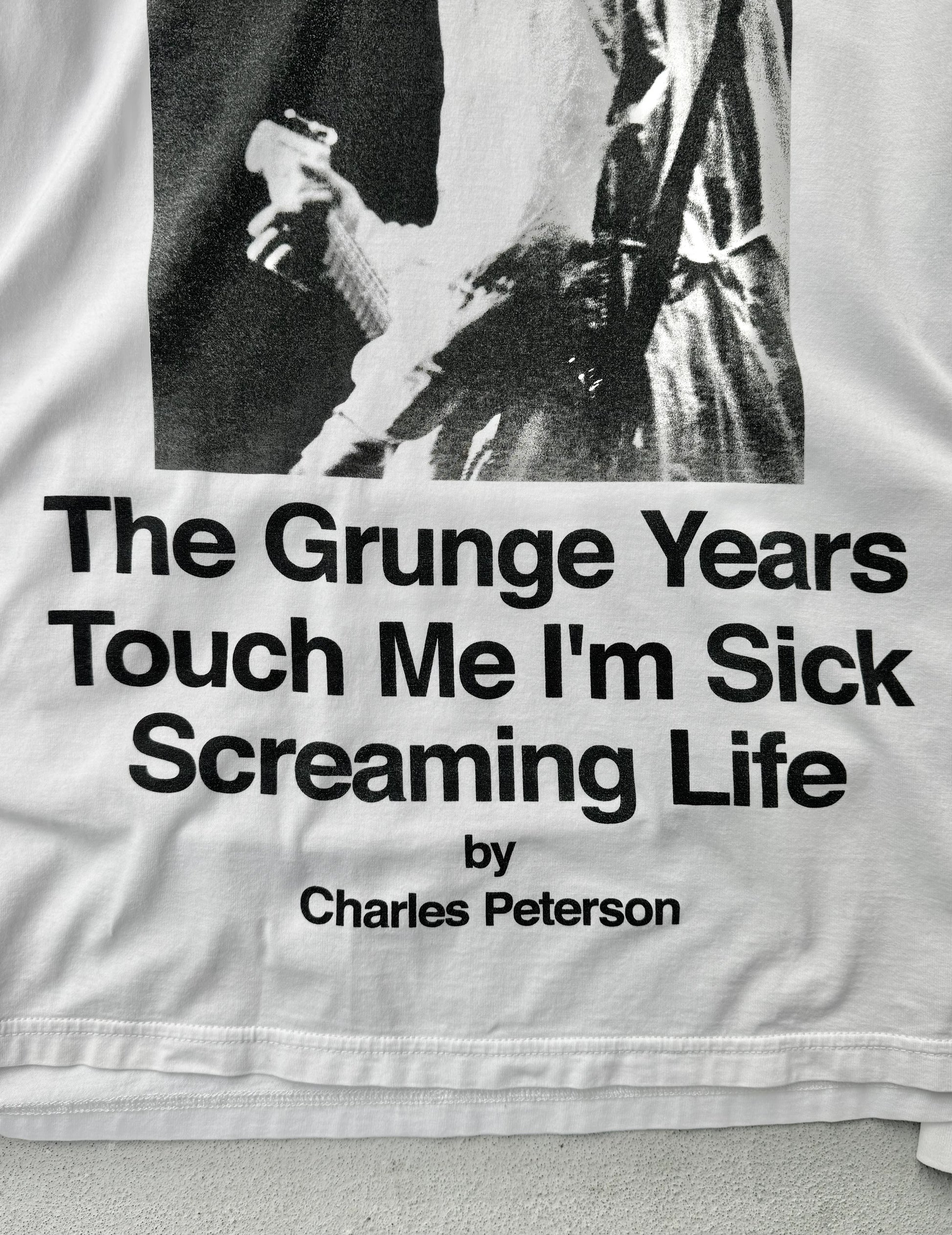 Text on a garment with a black and white photo of a person, featuring the quote 'The Grunge Years Touch Me I'm Sick Screaming Life' by Charles Peterson.