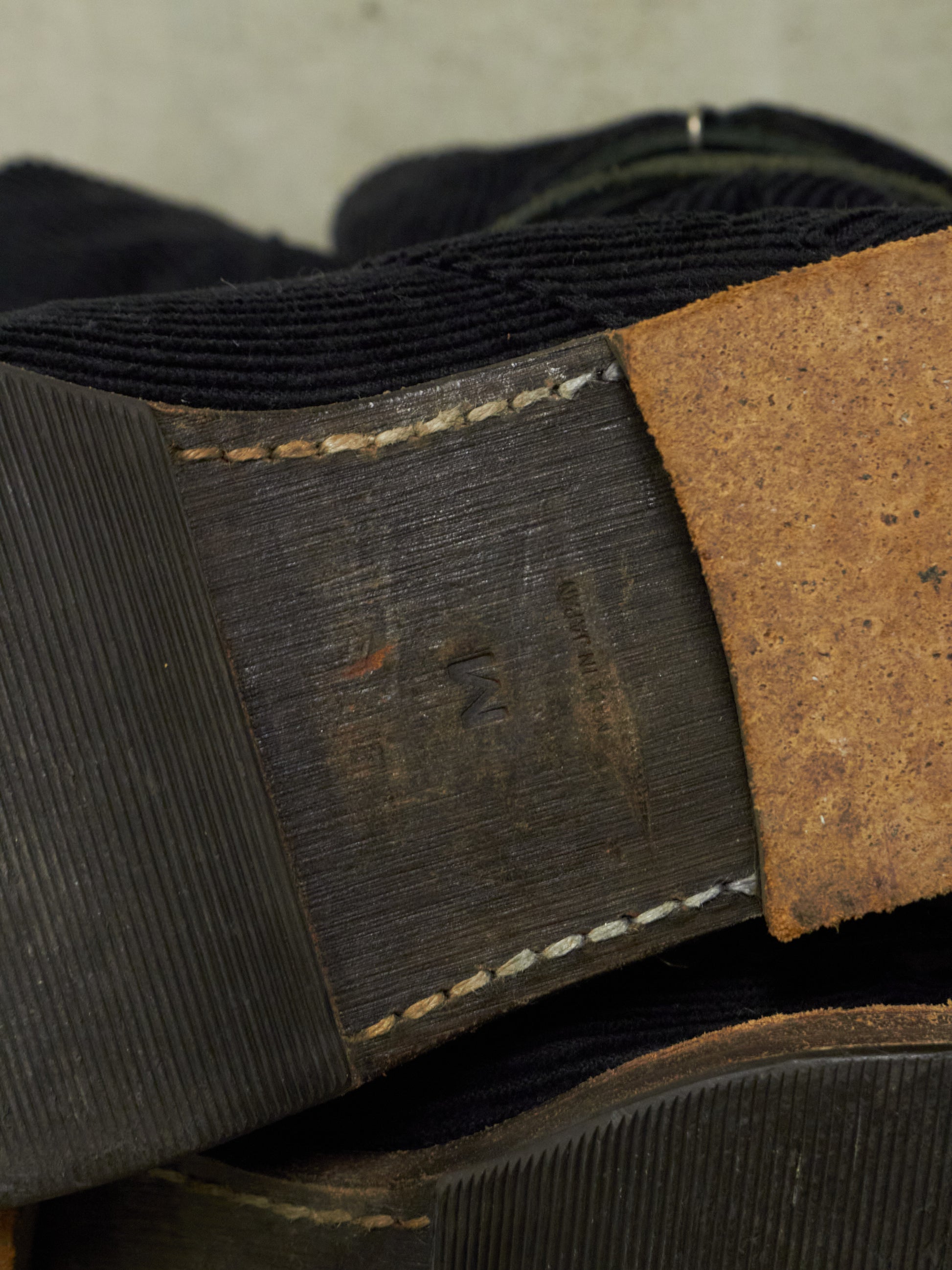 Close-up of a black belt with a brown leather tab on a gray background