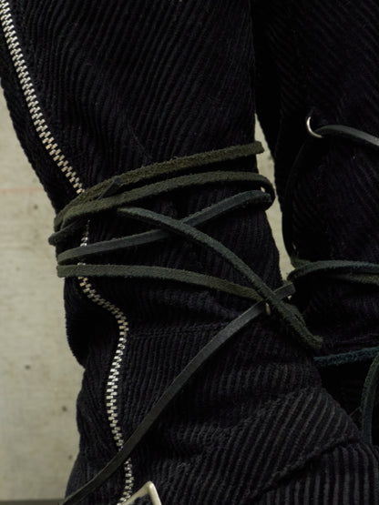 Close-up of a black corduroy jacket with green laces and zippers.