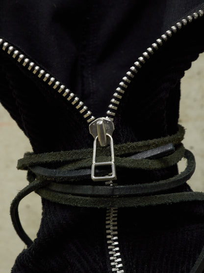 Close-up of a black jacket with a silver zipper and leather strap.