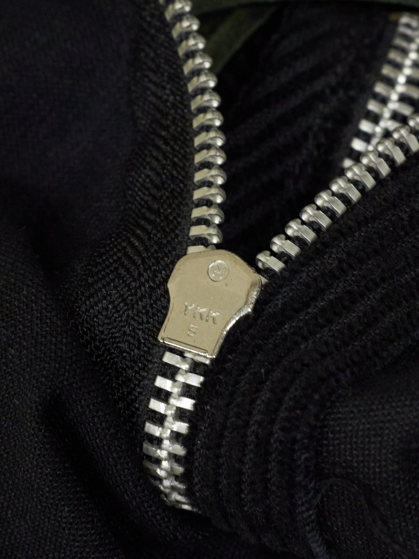 Close-up of a silver zipper on a black fabric background