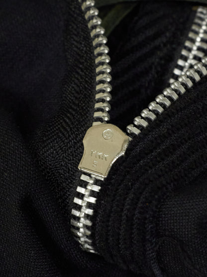 Close-up of a silver zipper on a black fabric background