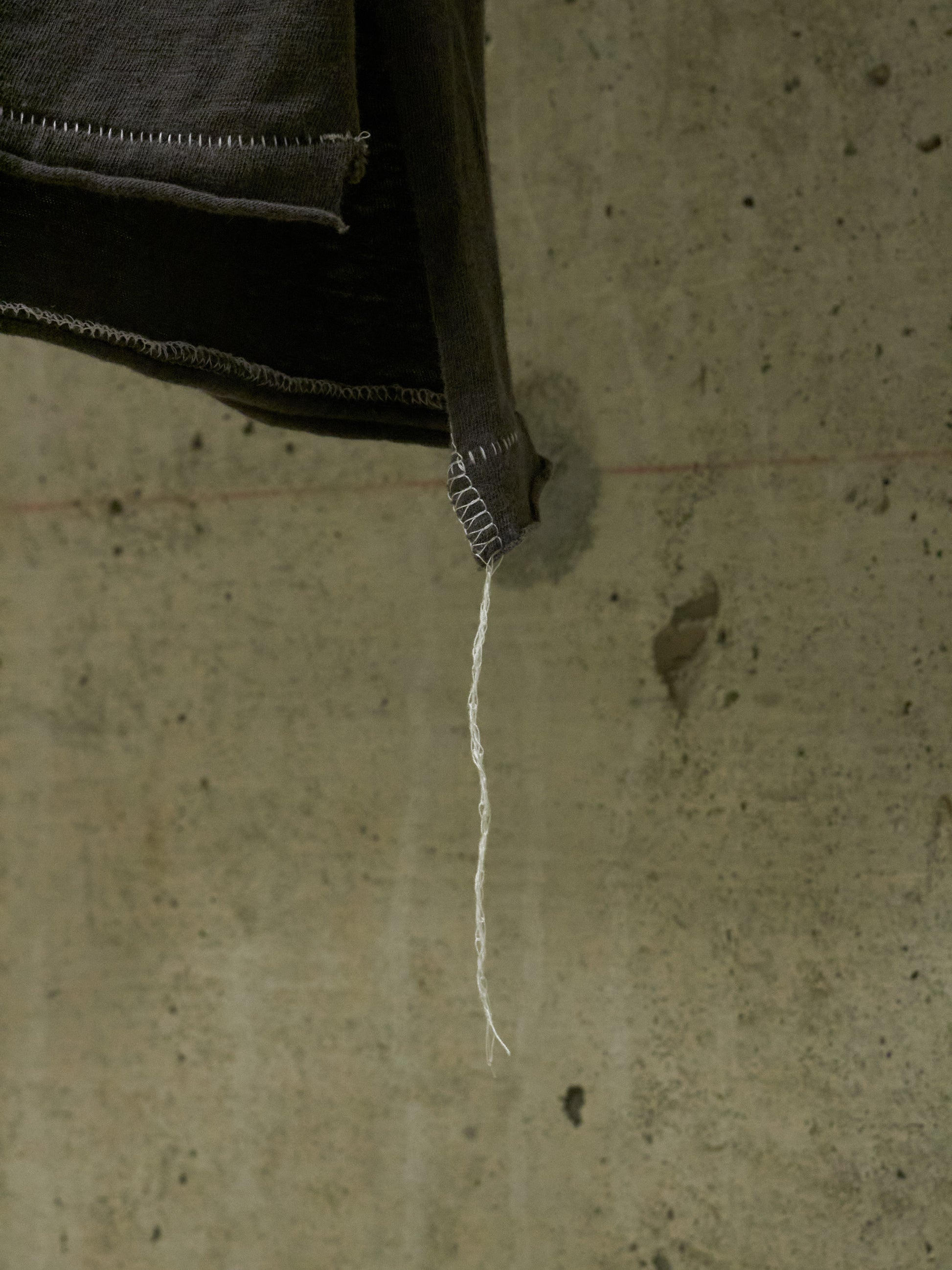 Close-up of a string hanging from a dark object on a textured surface
