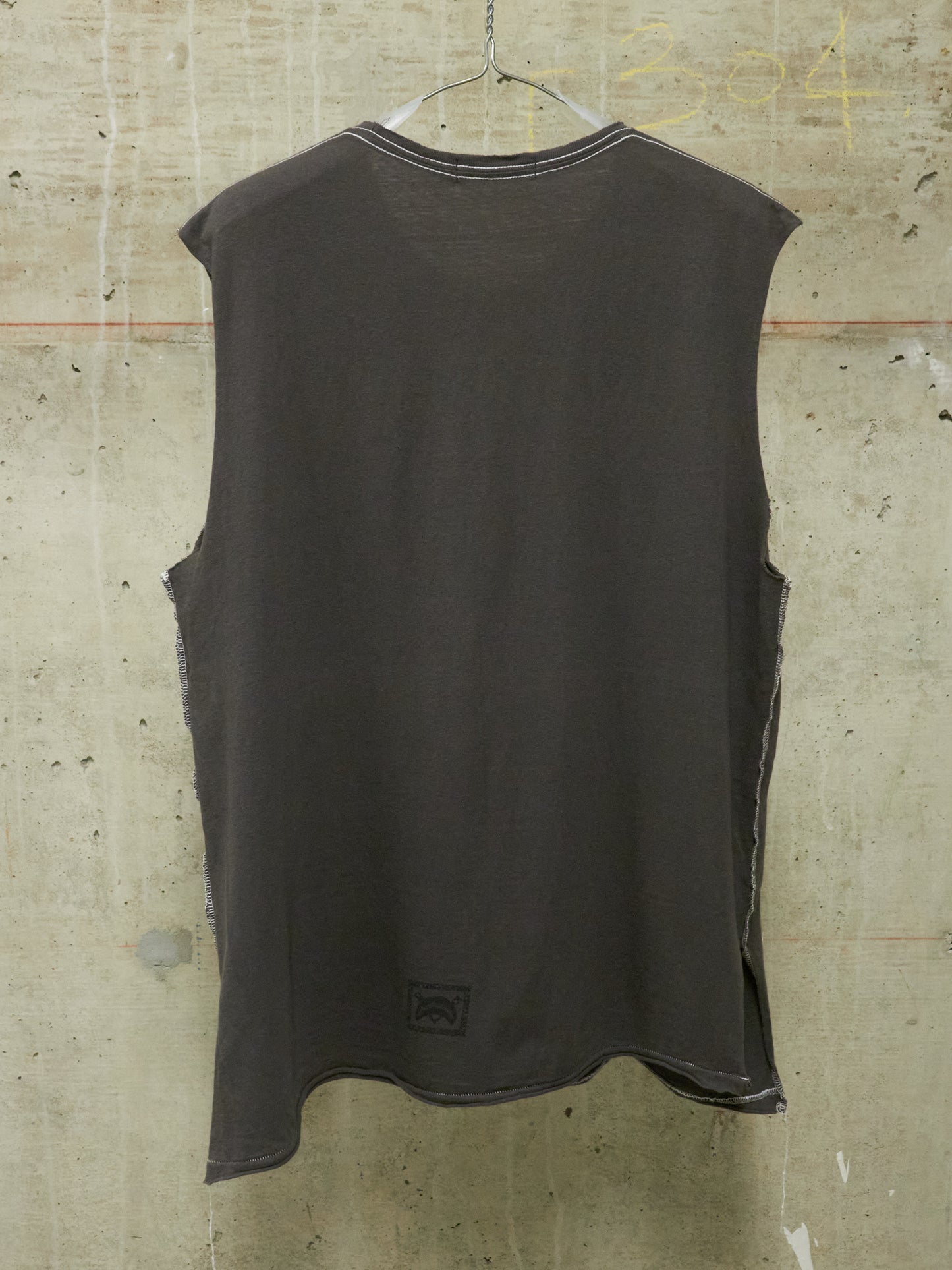 Dark sleeveless shirt hanging against a textured wall.