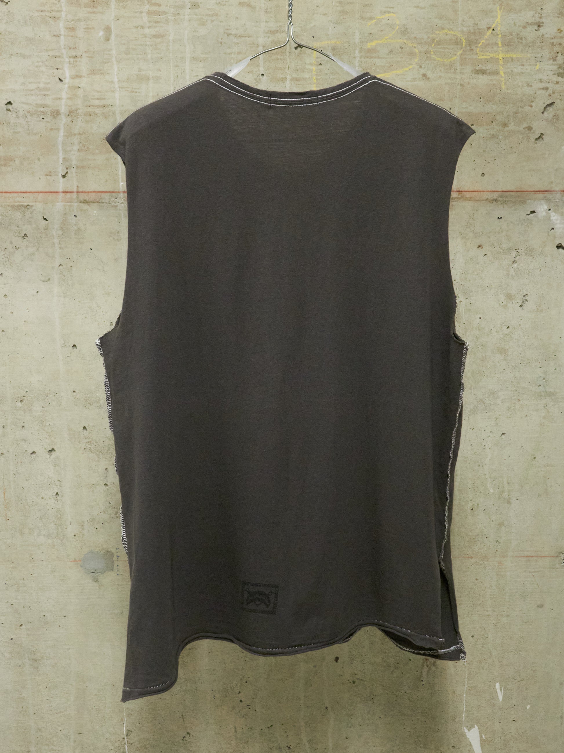 Dark sleeveless shirt hanging against a textured wall.