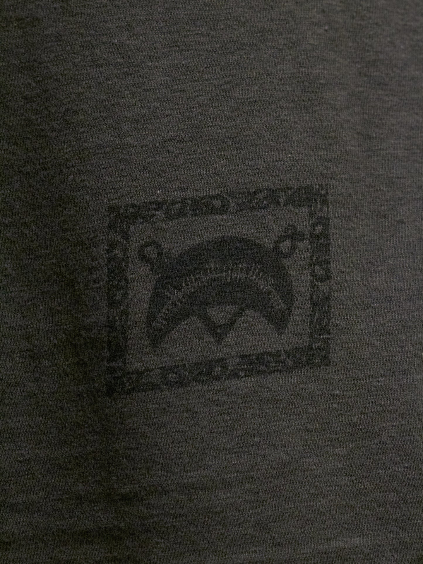 Close-up of a dark gray t-shirt with a logo on the chest.