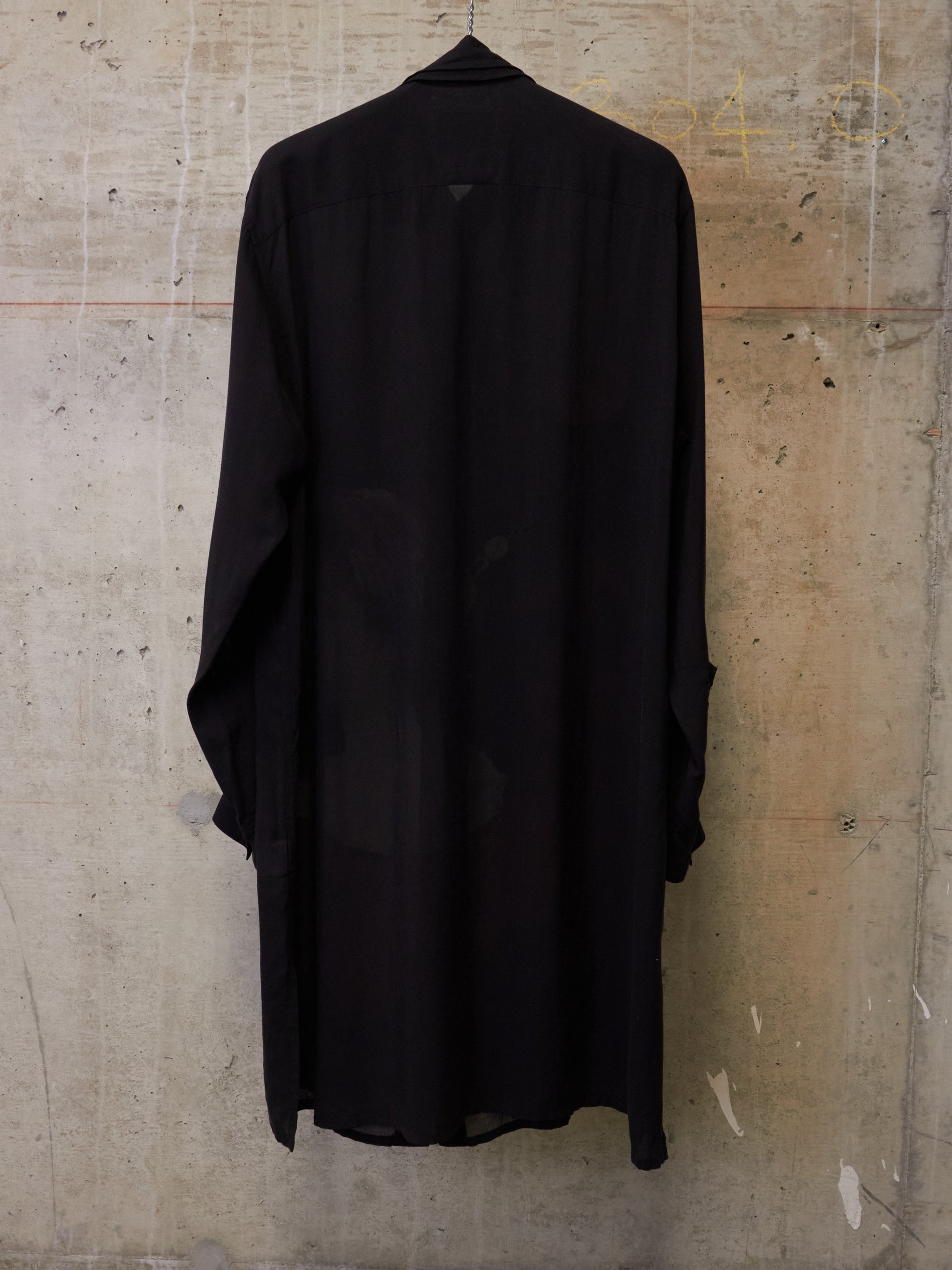 Black shirt hanging against a textured wall