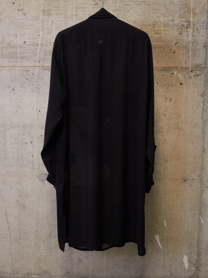 Black shirt hanging against a textured wall