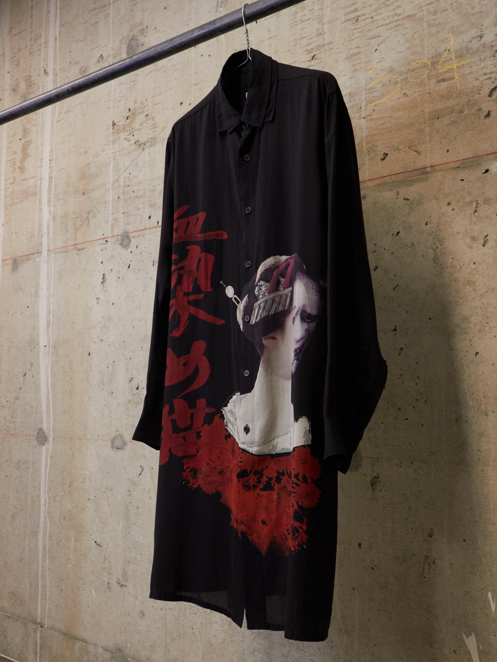 Black shirt with graphic design hanging against a textured wall