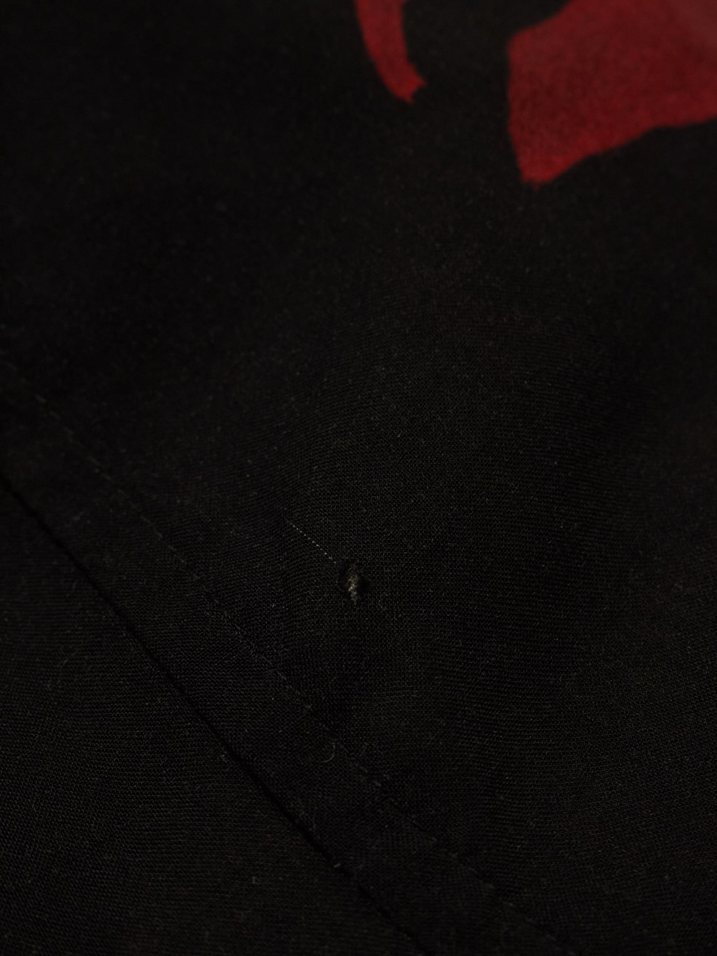 Close-up of a black fabric texture with a red object partially visible.