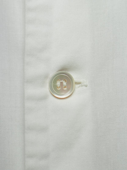 Close-up of a white textured fabric with a single round translucent button on the left side of a vertical seam.