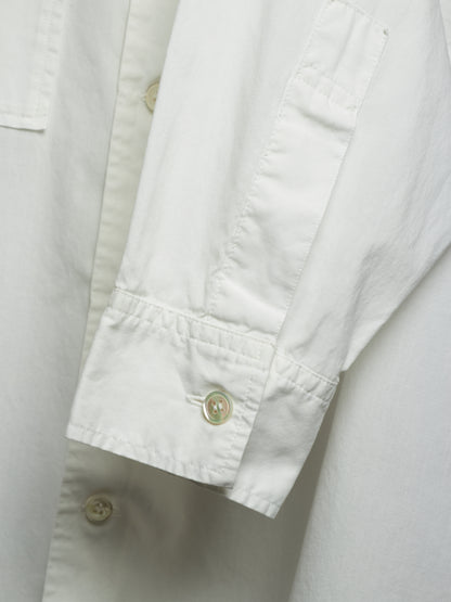 Close-up of a white long-sleeve button-up shirt showing the sleeve cuff with a button and the fabric texture.