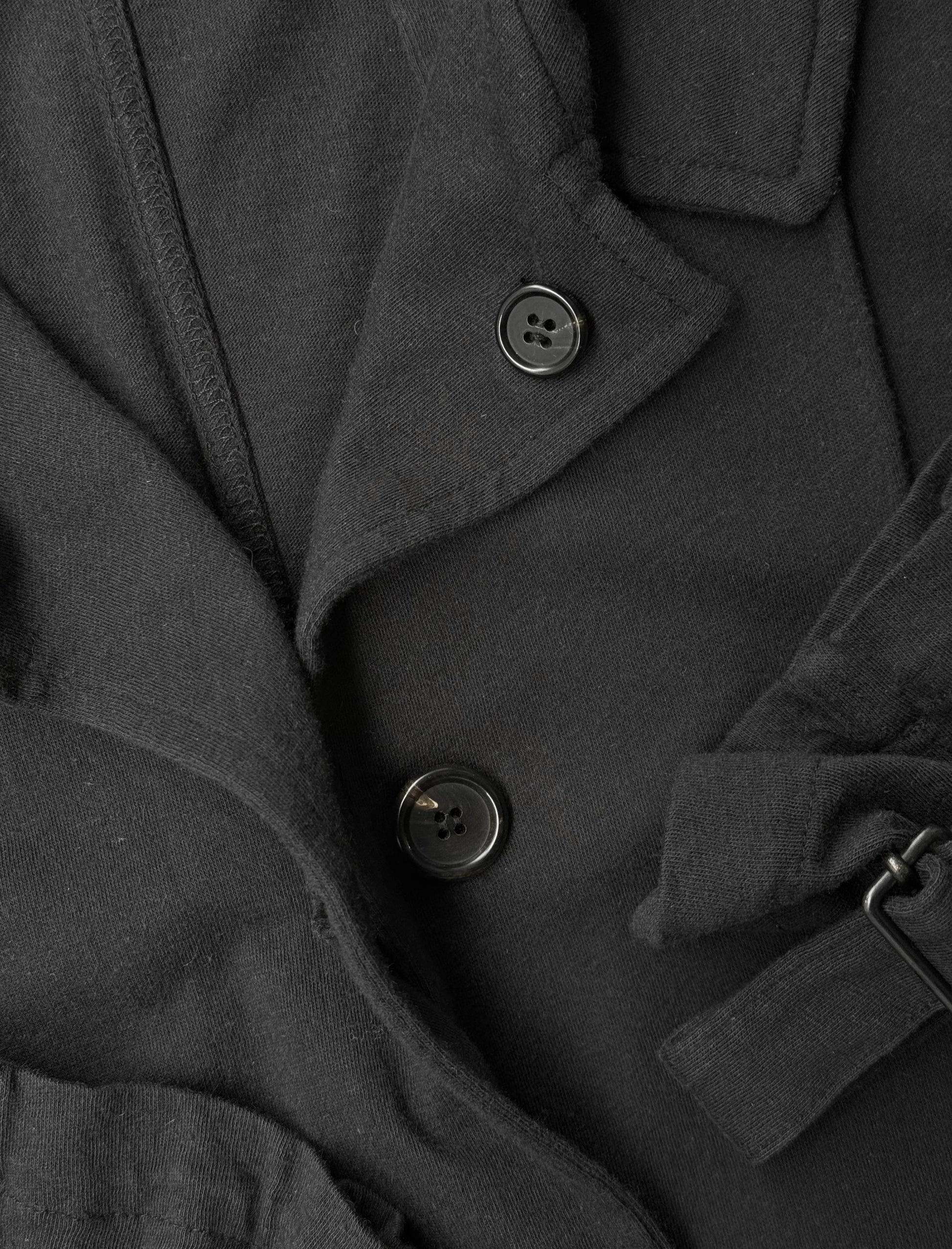 Close-up of a dark gray coat with buttons and a belt.
