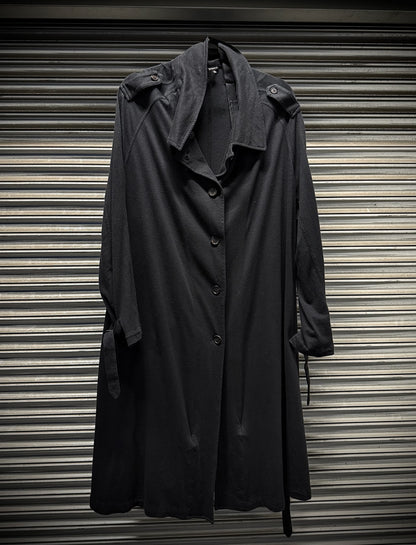 Dark gray trench coat hanging against a corrugated metal background