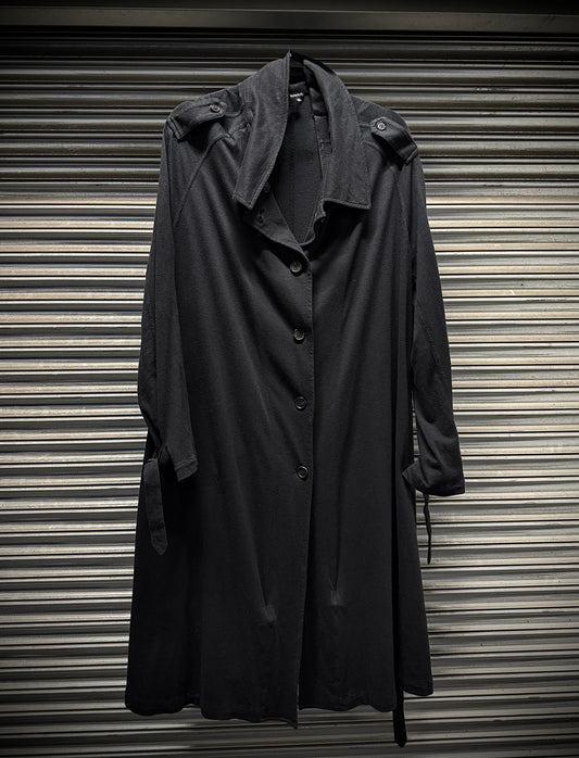 Dark gray trench coat hanging against a corrugated metal background