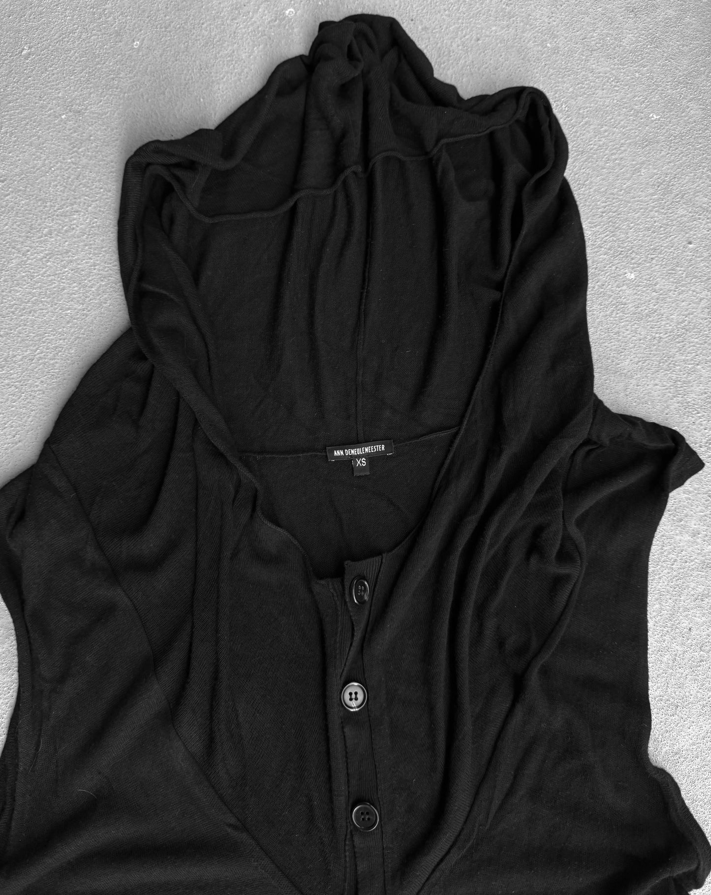 Black sleeveless shirt with buttons on a gray surface