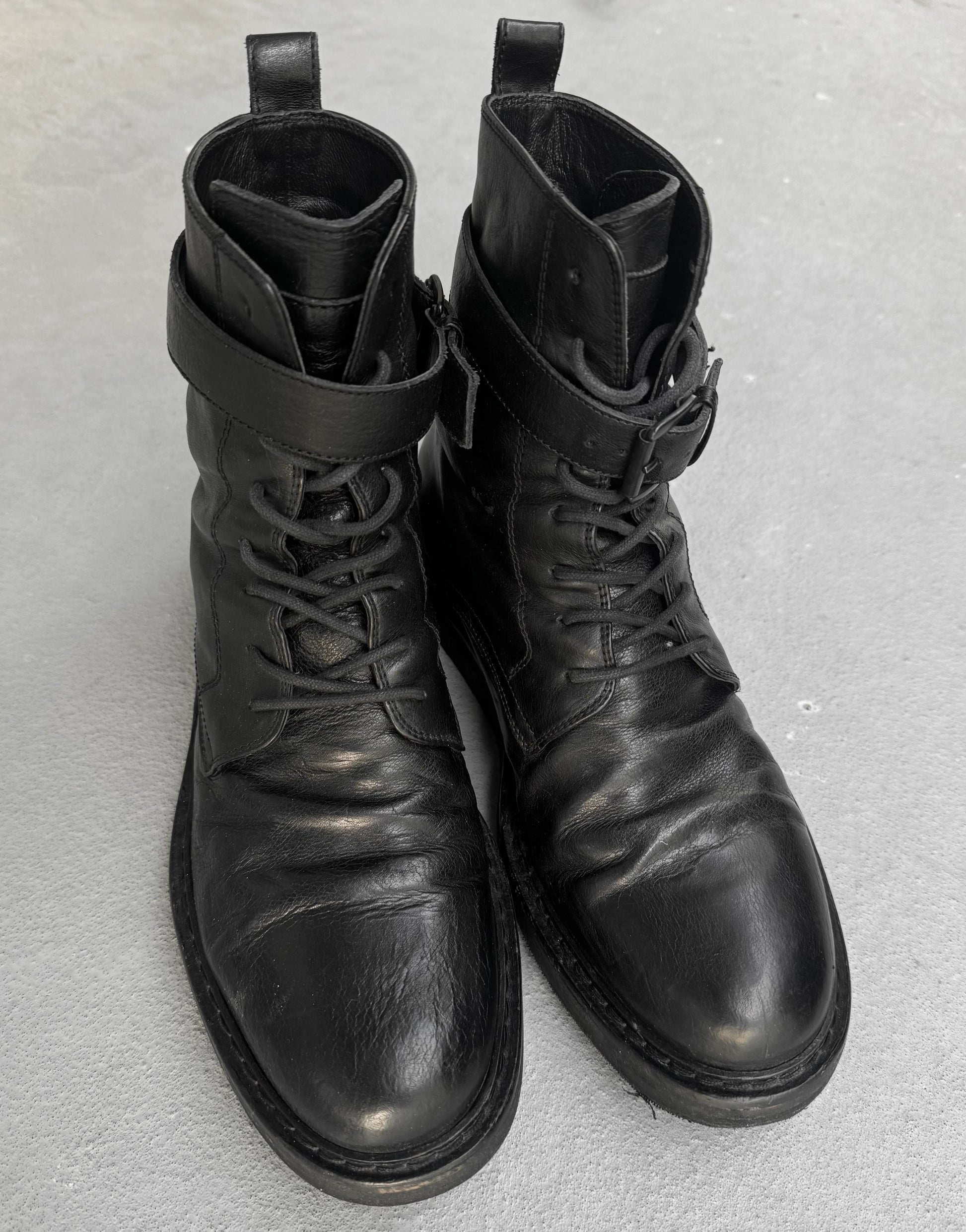 Pair of black leather boots on a gray background