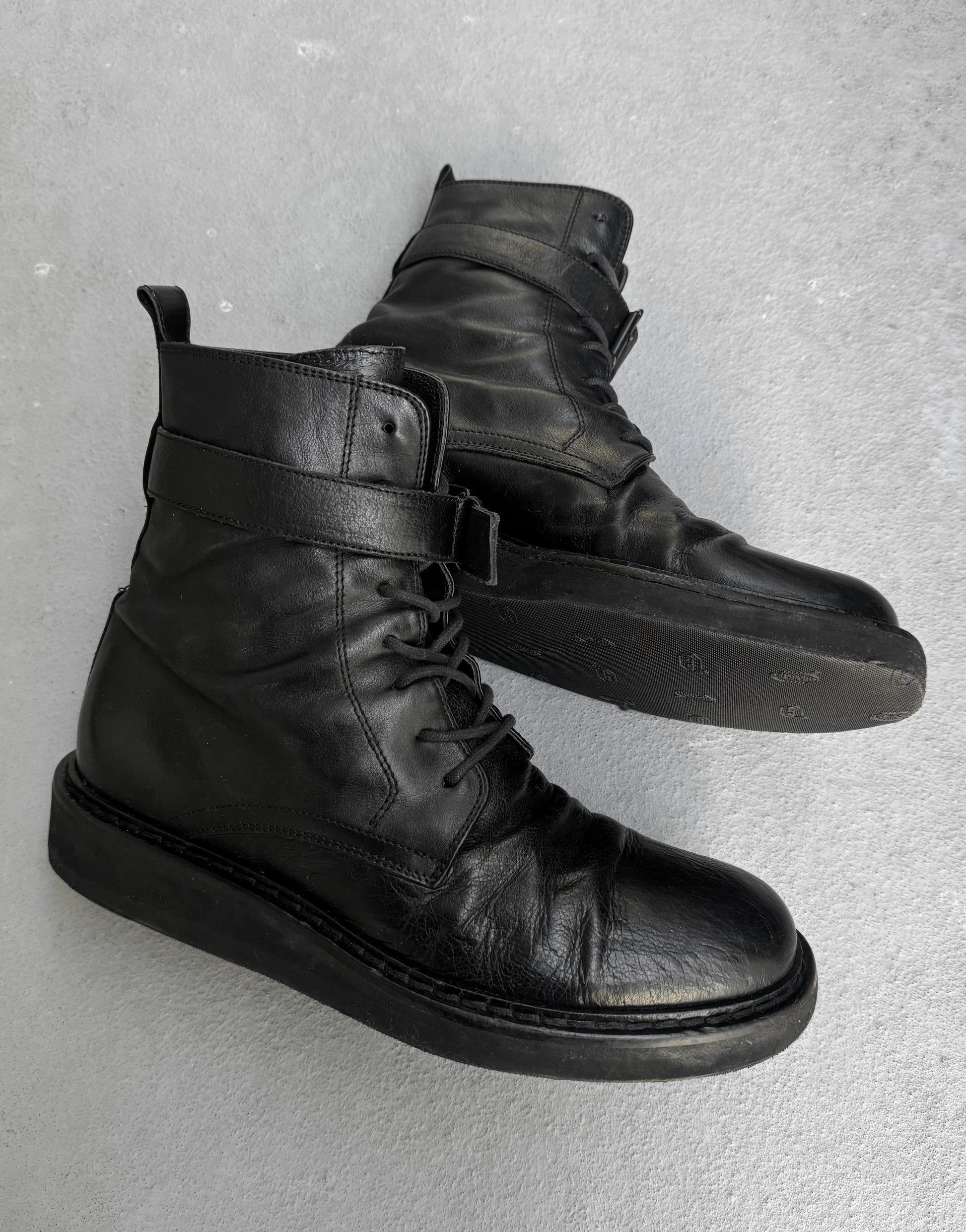 Pair of black leather boots on a gray background