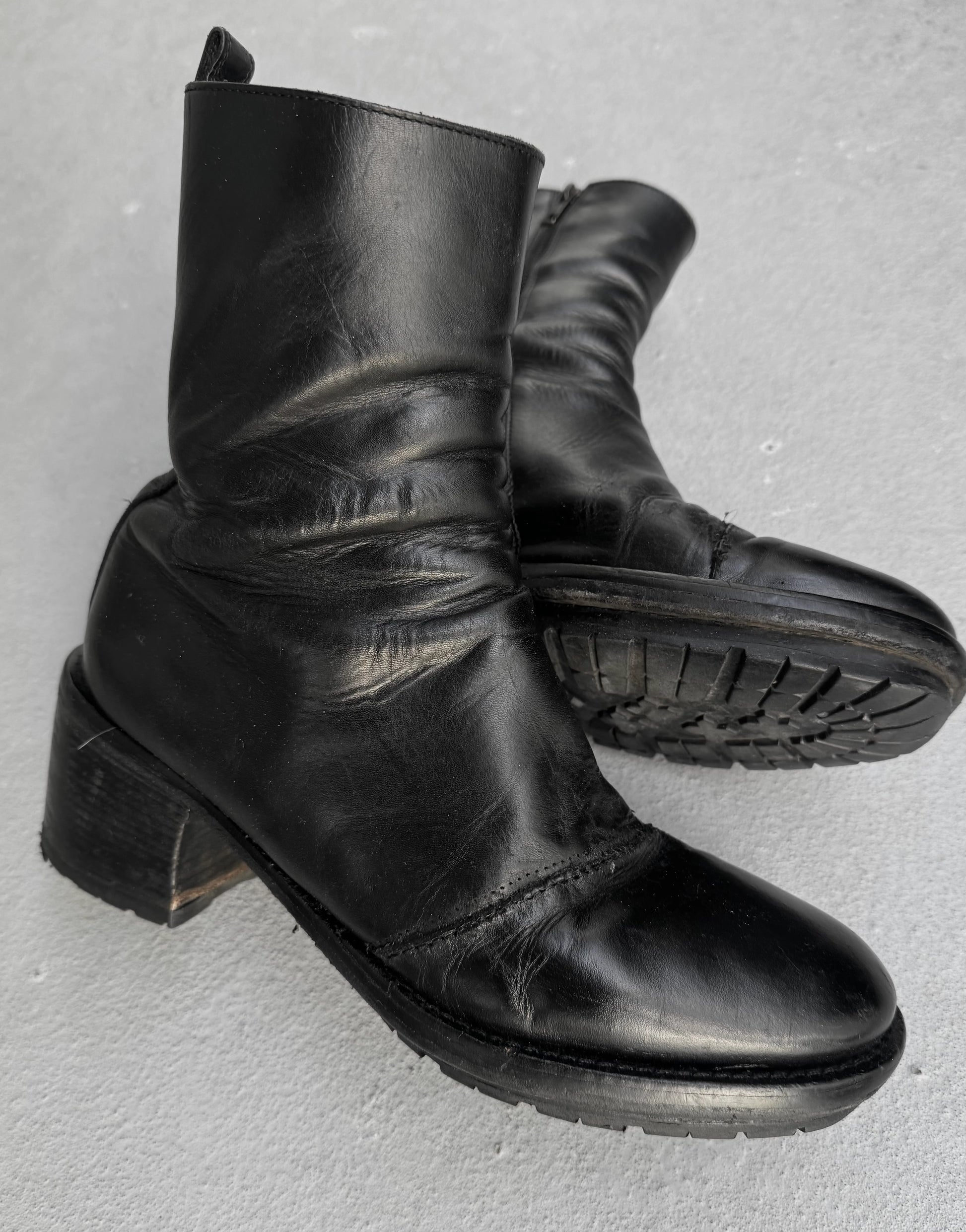 Pair of black leather boots on a gray background