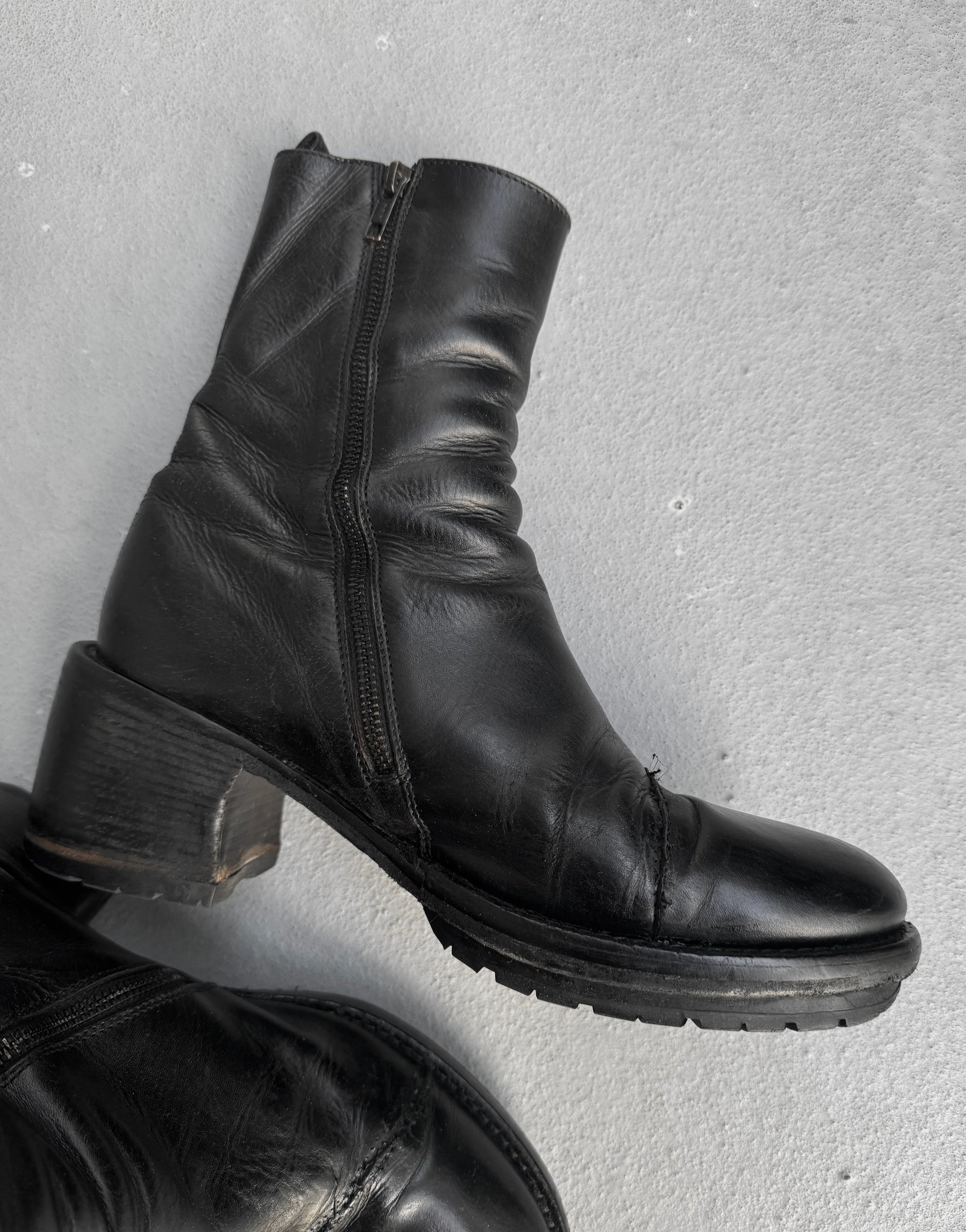 Black leather boots with a zipper on a gray background