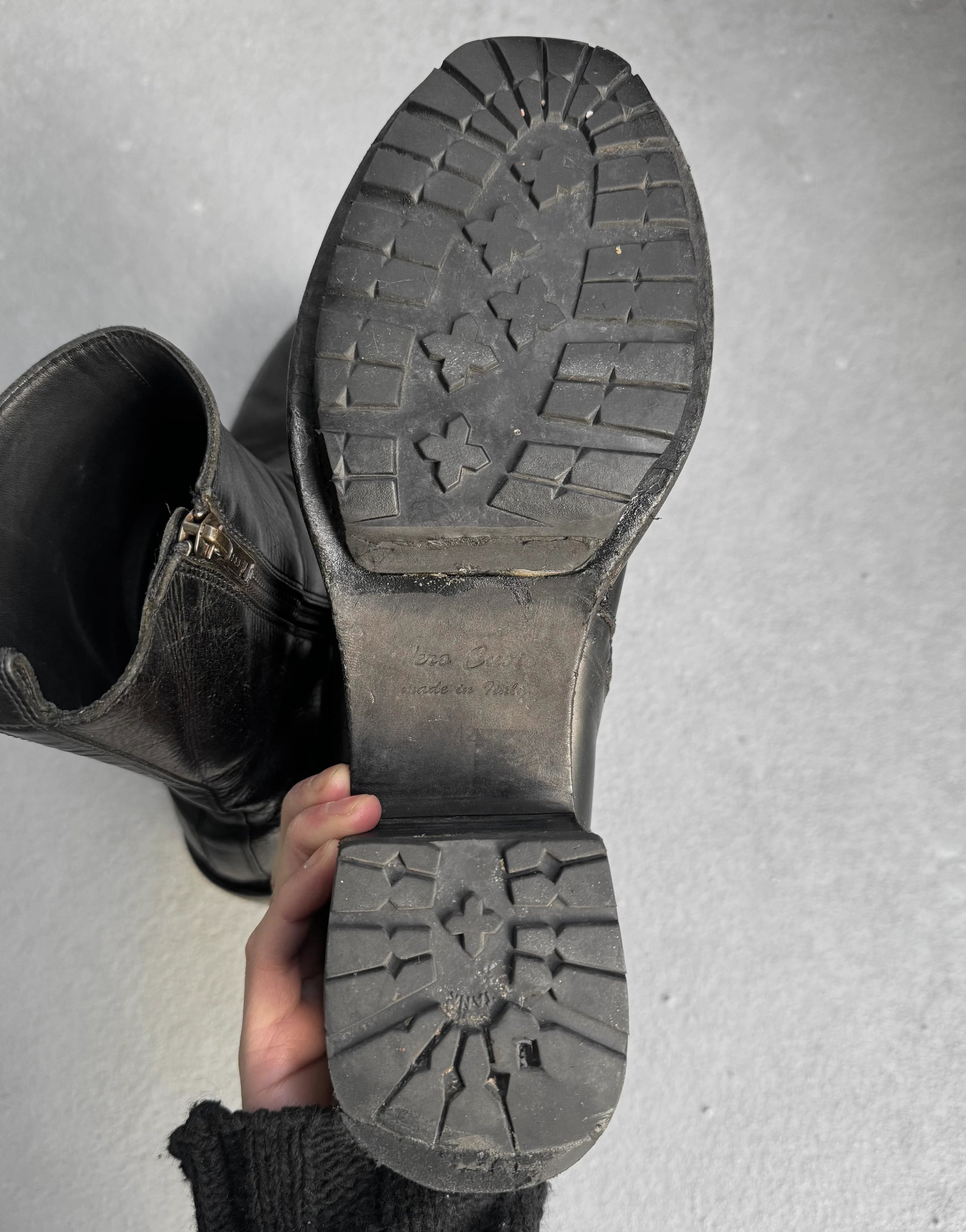 Black boot with a focus on the sole against a gray background