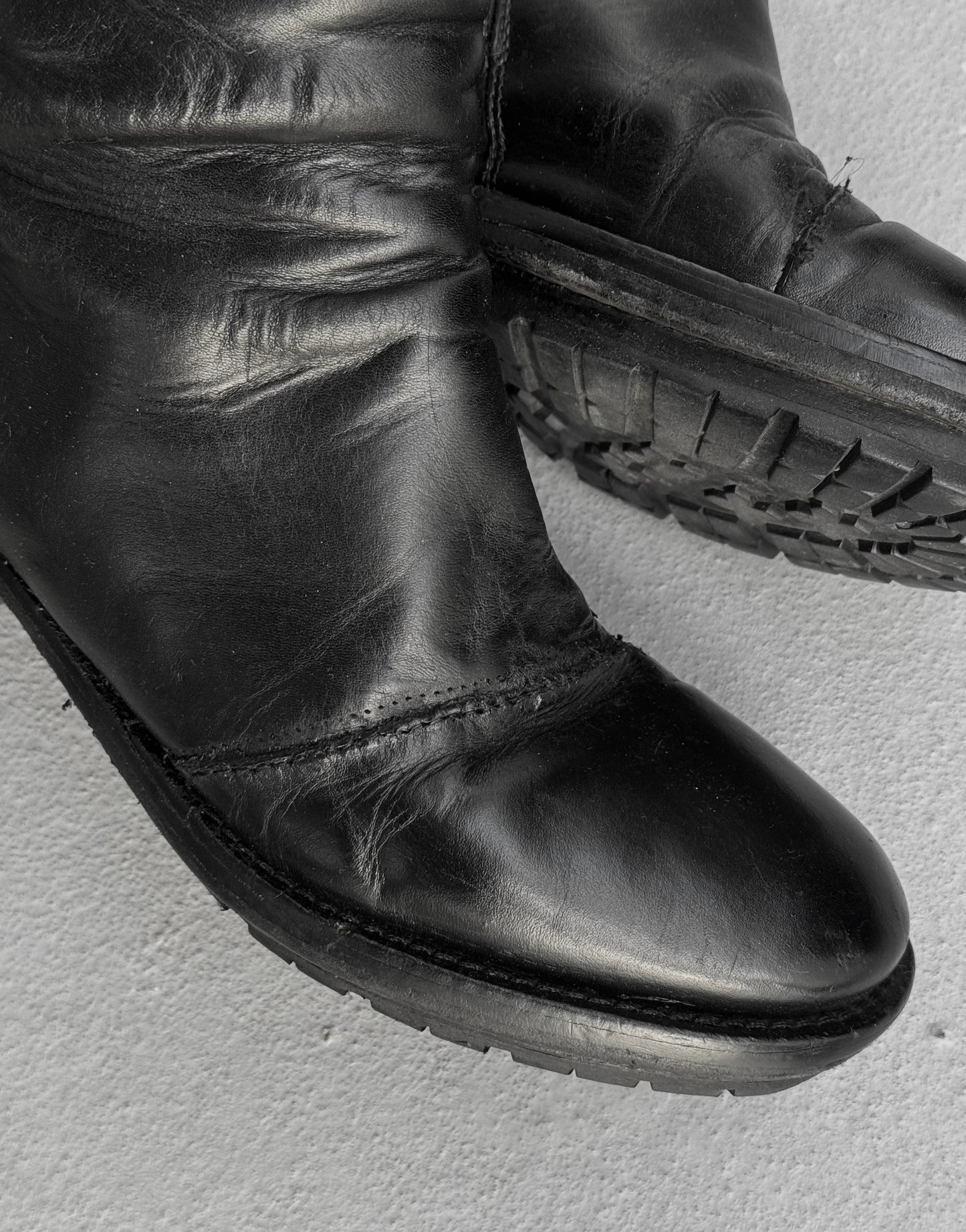 Black leather boot on a light gray background