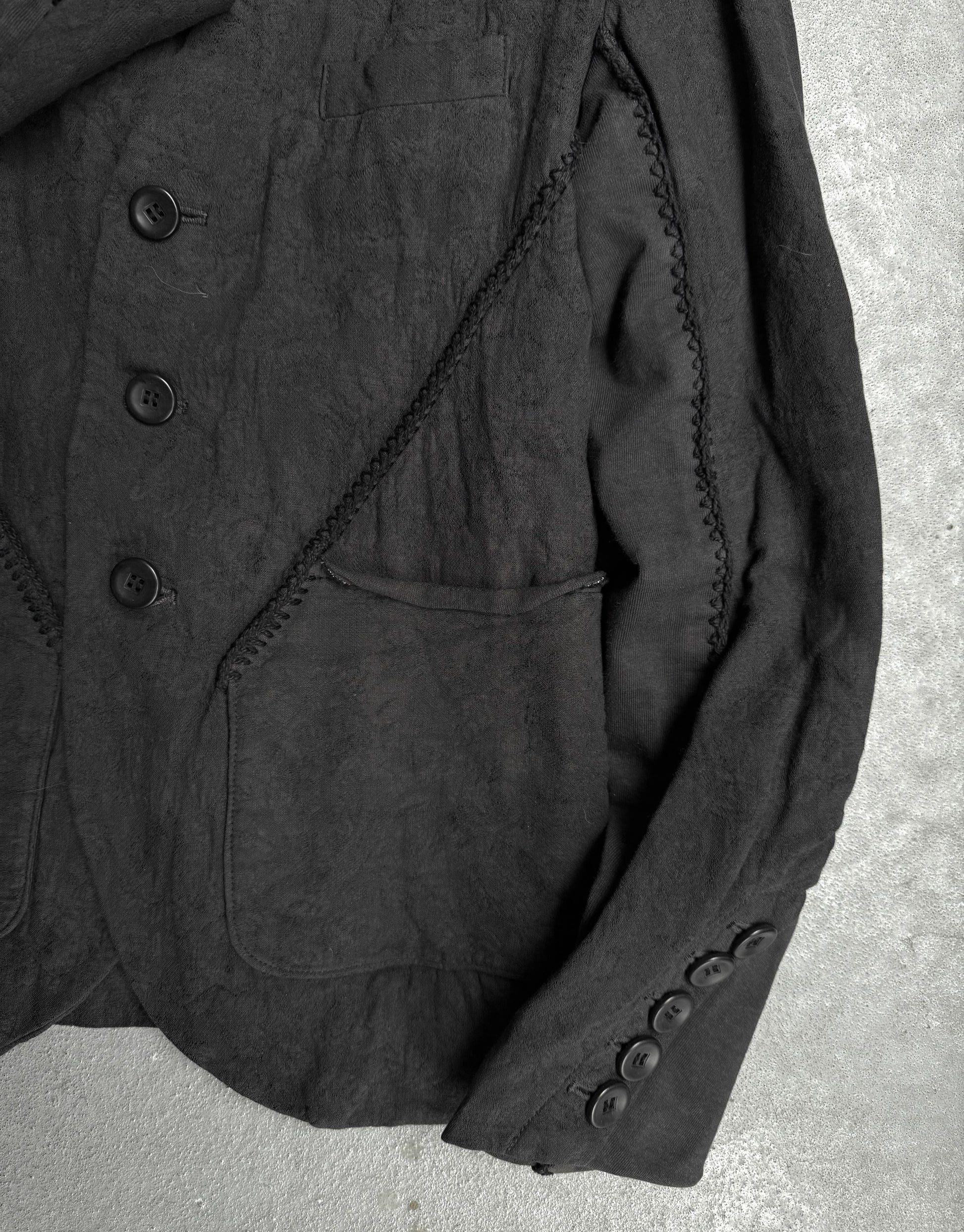 Close-up of a dark textured fabric jacket on a concrete surface