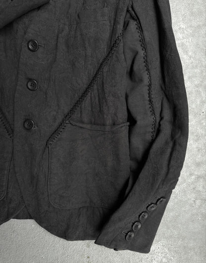 Close-up of a dark textured fabric jacket on a concrete surface