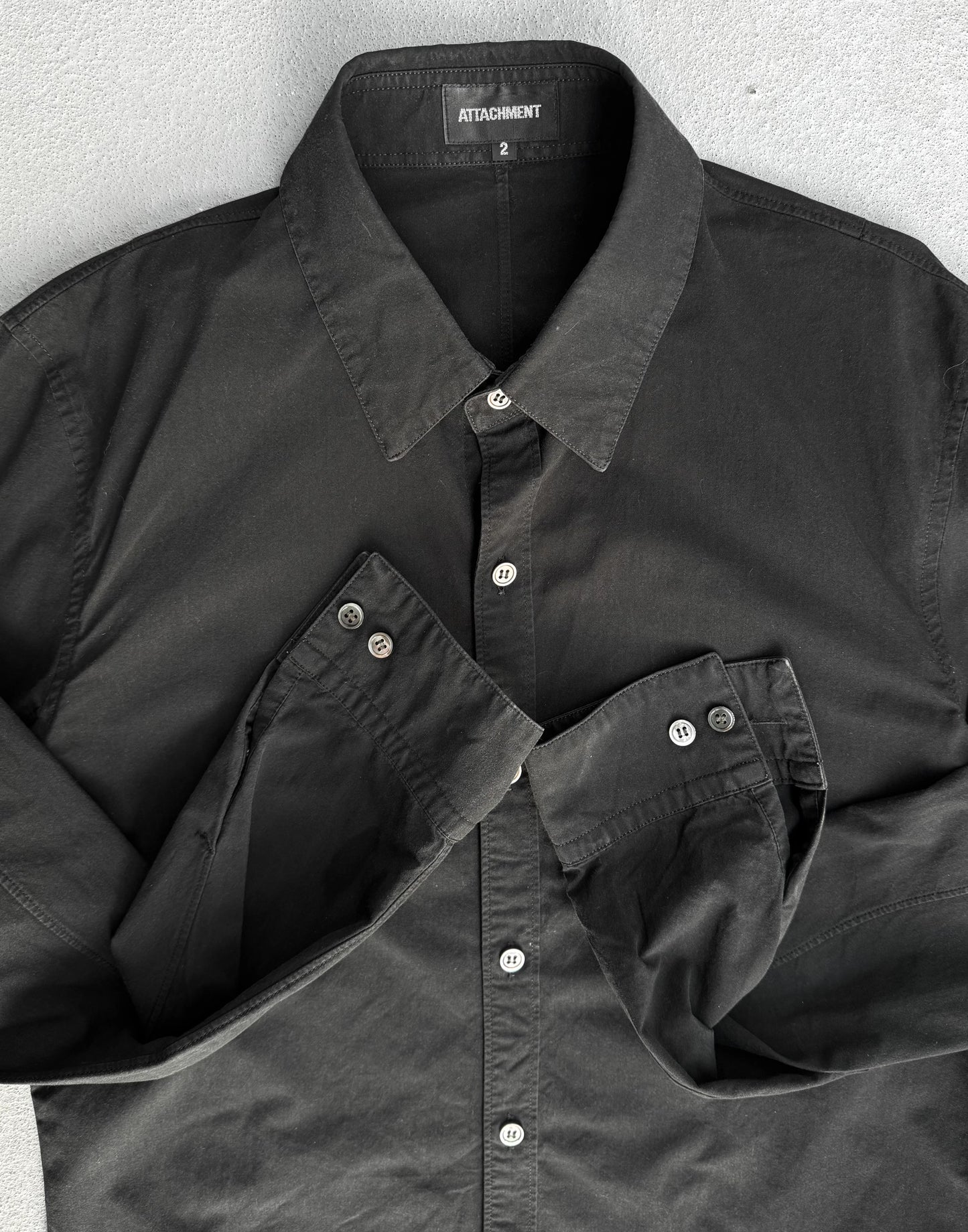 Black shirt with collar and button details on a gray background