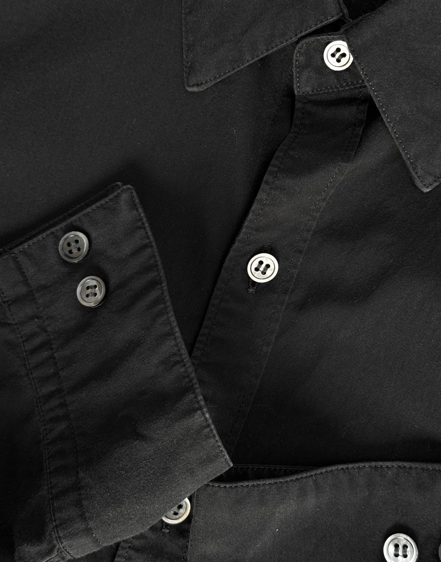 Close-up of a black shirt with buttons on a plain background