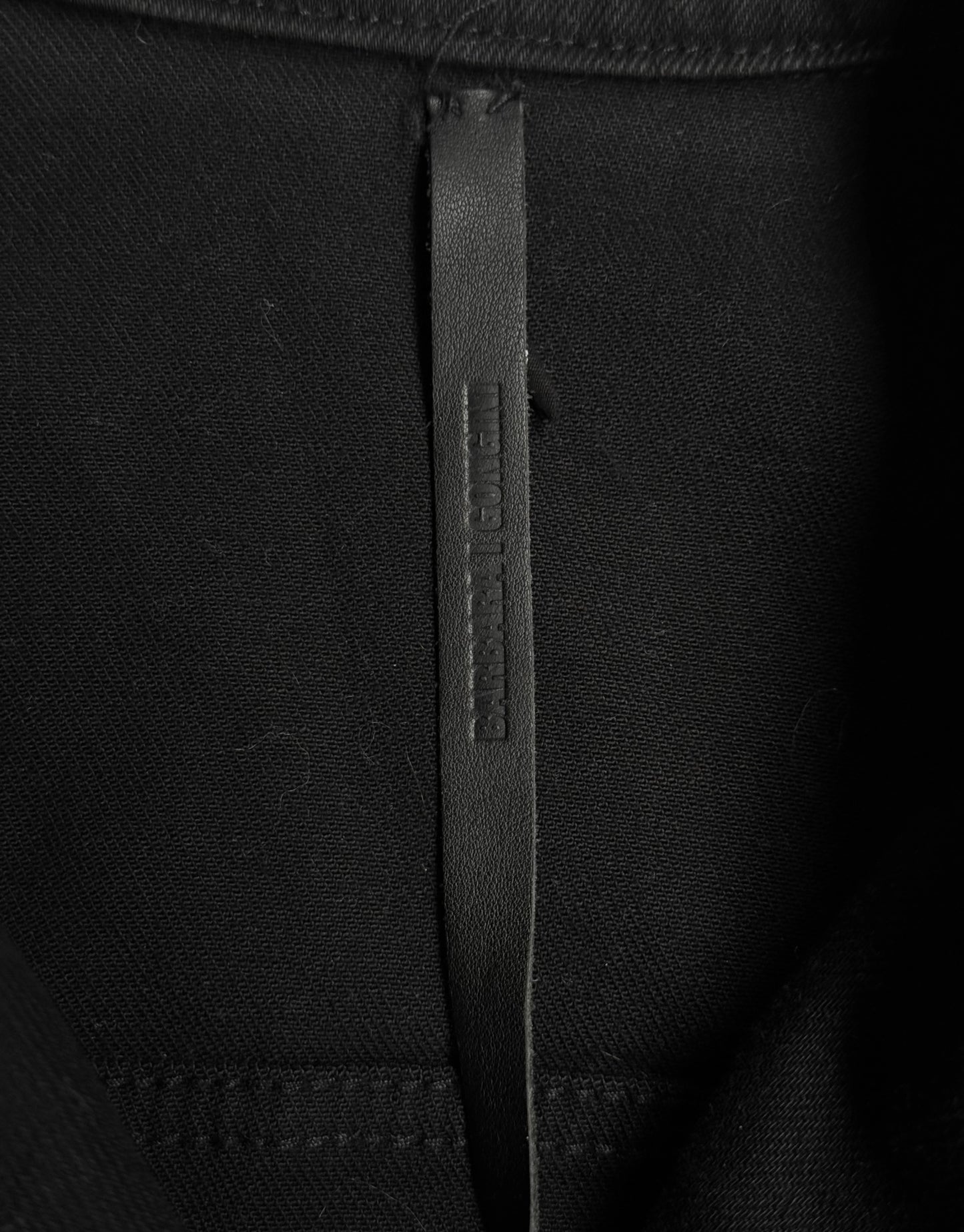 Close-up of a black fabric with a brand label on a black background